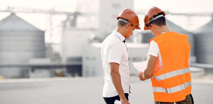 Engineers near the factory. Mtn in a helmet. Inspector looks at the building.